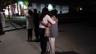 Unidentified people comfort each other as they stand near a business building where a shooting occurred in Orange, Calif., Wednesday, March 31, 2021