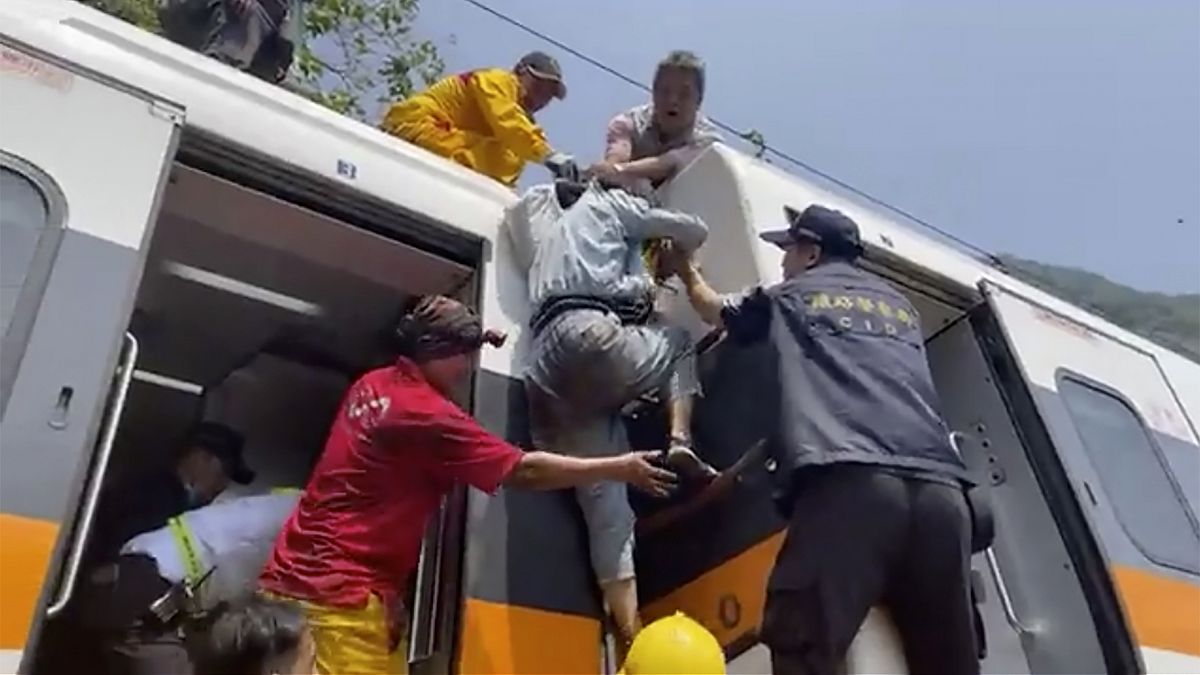 A screenshot from video released by hsnews.com.tw, shows a passenger being helped to climb out of a derailed train in Hualien County in eastern Taiwan. April 2, 2021.