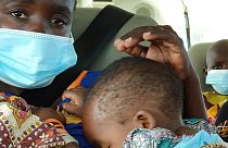 Uma mulher com uma criança ao colo é levada de avião de Palma para Pemba, em Moçambique