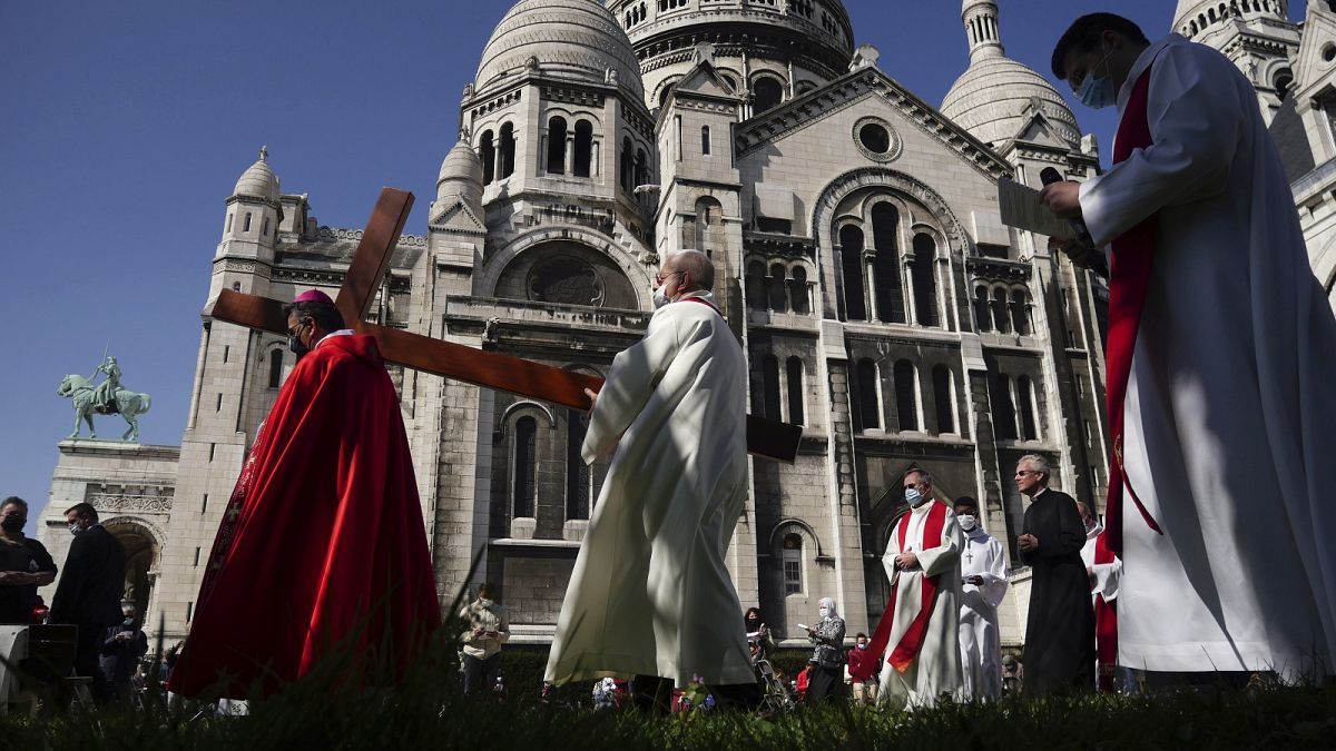 Archbishop Michel Aupetit, left, carries the holy cross at the Way of the Cross ceremony as part of the Holy Easter celebration, in the Sacre Coeur basilica, in Paris, France.