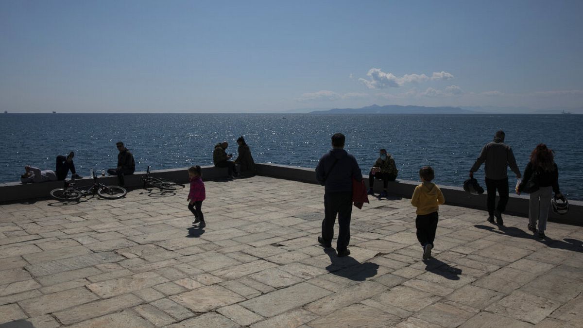 People enjoy a sunny day at a square at Piraeus port town near Athens