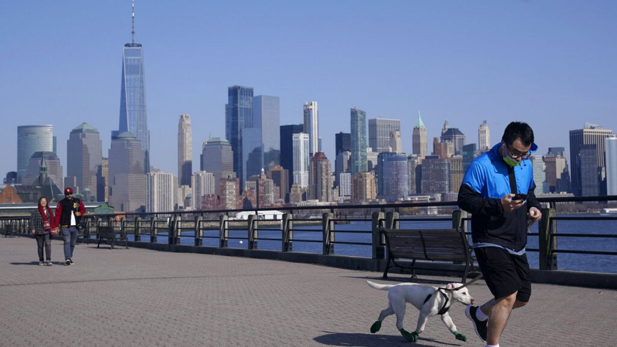 people enjoy the warming weather and a view of lower Manhattan at Liberty State Park in Jersey City