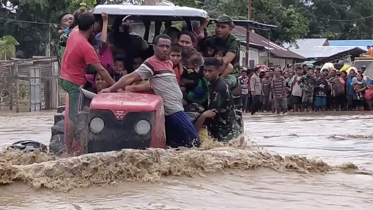 جنود أندونيسيين يستخدمون جراراً لمساعدة السكان على عبور طريق غمرته مياه الفيضانات في مالاكا تينجا بمقاطعة نوسا تينجارا الشرقية