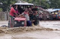 جنود أندونيسيين يستخدمون جراراً لمساعدة السكان على عبور طريق غمرته مياه الفيضانات في مالاكا تينجا بمقاطعة نوسا تينجارا الشرقية