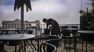 A waiter cleans chairs at the Portas do Sol viewpoint in Lisbon as the Portuguese government eased coronavirus restrictions.