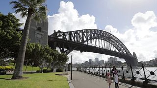 A woman and 2 children walk under the Harbour Bridge in a popular area in Sydney, Australia, Tuesday, April 6, 2021. 