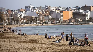 Primeros turistas en una playa de Mallorca (España)