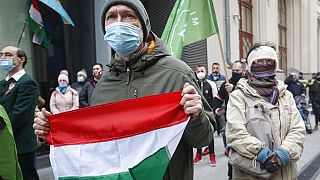 A man holds a Hungarian flag during a protest in Budapest, Hungary, Monday, March 15, 2021. 