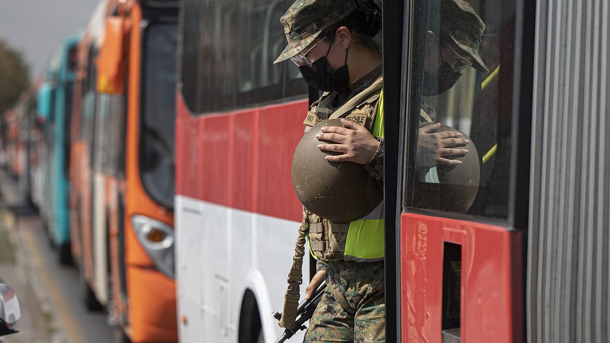 Una soldado sale de un autobús en un puesto de control en Santiago de Chile tras verificar los permisos de tránsito de los pasajeros.