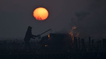 A winegrower burns a bale of straw in the vineyards to protect them from frost on April 7, 2021 as the sun rises at the heart of the Vouvray vineyard in Touraine, France
