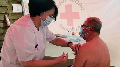 A Red Cross volunteer administers the AstraZeneca COVID-19 vaccine to a man in a vaccination center of Saint-Jean-de-Luz, southwestern France, Thursday, April 8, 2021. A Red Cross volunteer administers the AstraZeneca COVID-19 vaccine to a man in a vaccination center of Saint-Jean-de-Luz, southwestern France, Thursday, April 8, 2021.