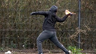 A young man throws a petrol bomb at police officers in the Springfield Road area of Belfast