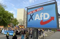 This picture taken May 1, 2019 shows AfD supporters walkin along a party elections poster in Erfurt, Germany.