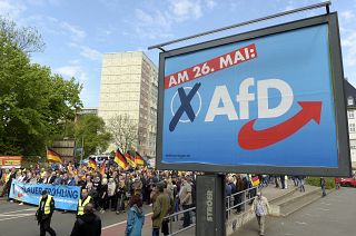 This picture taken May 1, 2019 shows AfD supporters walkin along a party elections poster in Erfurt, Germany. 