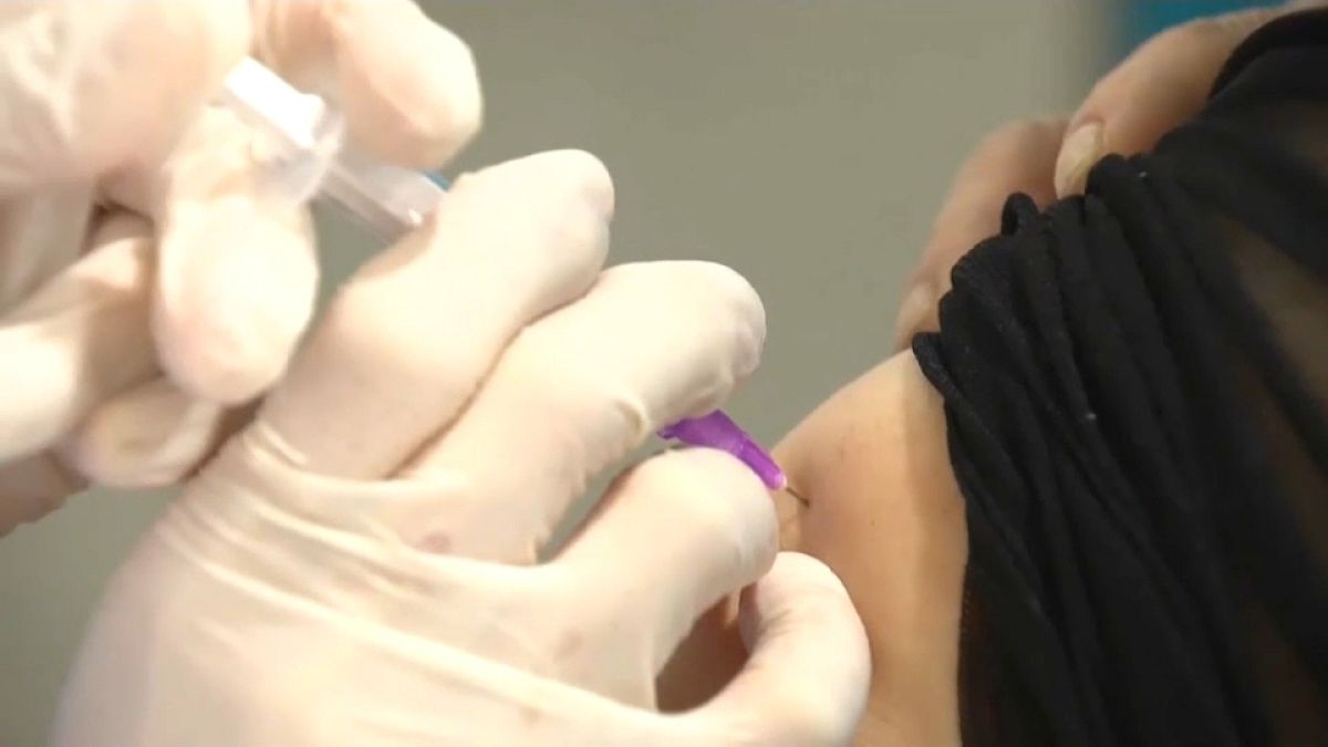 Un sanitario pone la dosis de una vacuna china a un paciente en un centro de vacunación