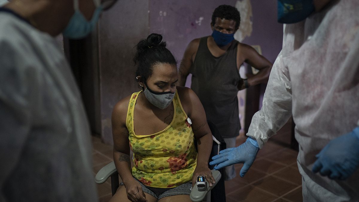 Mobile Emergency Care Service (SAMU) worker Elias Anjo, right, checks a patient suspected of having COVID-19 at her house in Duque de Caxias, Brazil.