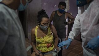 Mobile Emergency Care Service (SAMU) worker Elias Anjo, right, checks a patient suspected of having COVID-19 at her house in Duque de Caxias, Brazil.