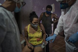Mobile Emergency Care Service (SAMU) worker Elias Anjo, right, checks a patient suspected of having COVID-19 at her house in Duque de Caxias, Brazil.