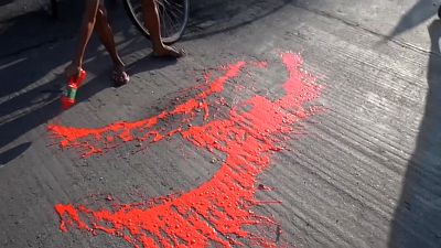 Anti-coup protestors splashing red paint on street to symbolise the blood shed by their movement