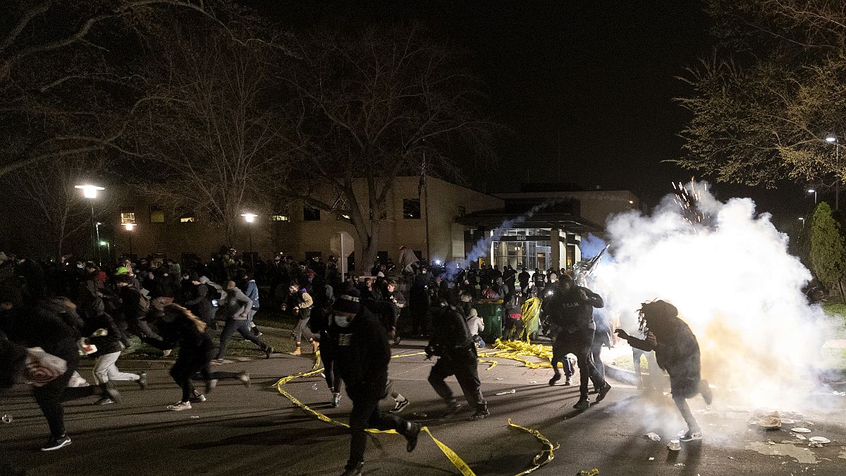 People run as police attempt to disperse the crowd at the Brooklyn Center Police Department, late Sunday, April 11, 2021, in Brooklyn Center, Minn.