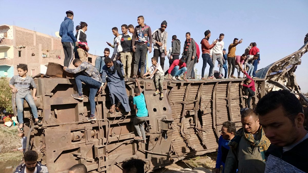 Egyptians gather around mangled train carriages at the scene of a train accident that killed at least 18 people and wounded 200 others including children, in Sohag, Egypt