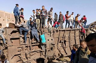 Egyptians gather around mangled train carriages at the scene of a train accident that killed at least 18 people and wounded 200 others including children, in Sohag, Egypt