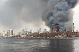 Fire burning in Nevskaya Manufaktura building, emergency vehicles on Neva river's bank