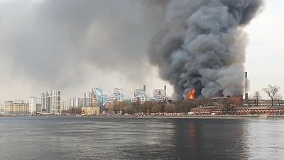 Fire burning in Nevskaya Manufaktura building, emergency vehicles on Neva river's bank