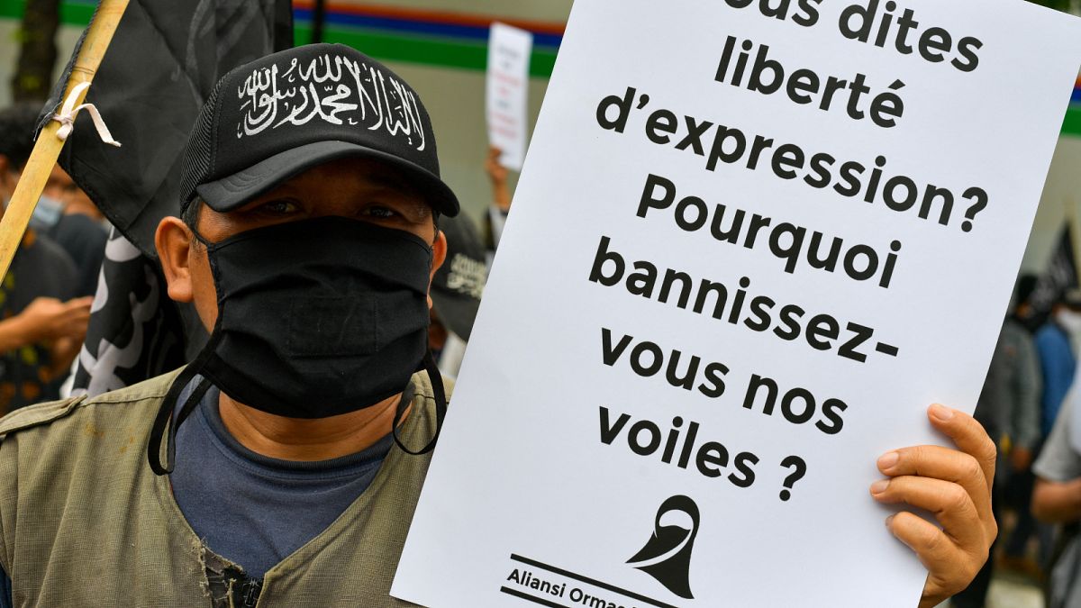 متظاهرون مسلمون يرفعون لافتات خلال مظاهرة مناهضة للرئيس الفرنسي إيمانويل ماكرون.