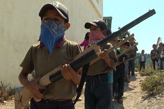 Child wearing a mask holds a replica rifle 