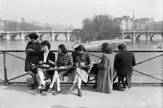 Young women draw on the Pont des Arts in Paris on the first warm spring days. March 1946