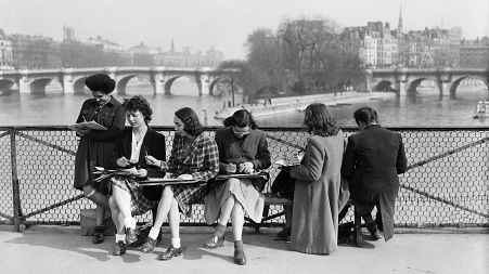 Young women draw on the Pont des Arts in Paris on the first warm spring days. March 1946