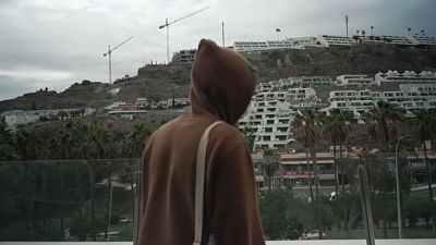 Un migrante mira el paisaje desde el balcón del hotel que le acoge