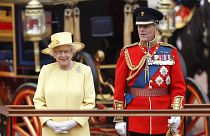 Britain's Queen Elizabeth II, and Prince Philip take a salute as the Guards march past outside Buckingham Palace on June 16, 2012.