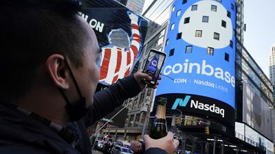 File-Coinbase employee Daniel Huynh holds a celebratory bottle of champagne as he photographs outside the Nasdaq MarketSite, in New York's Times Square
