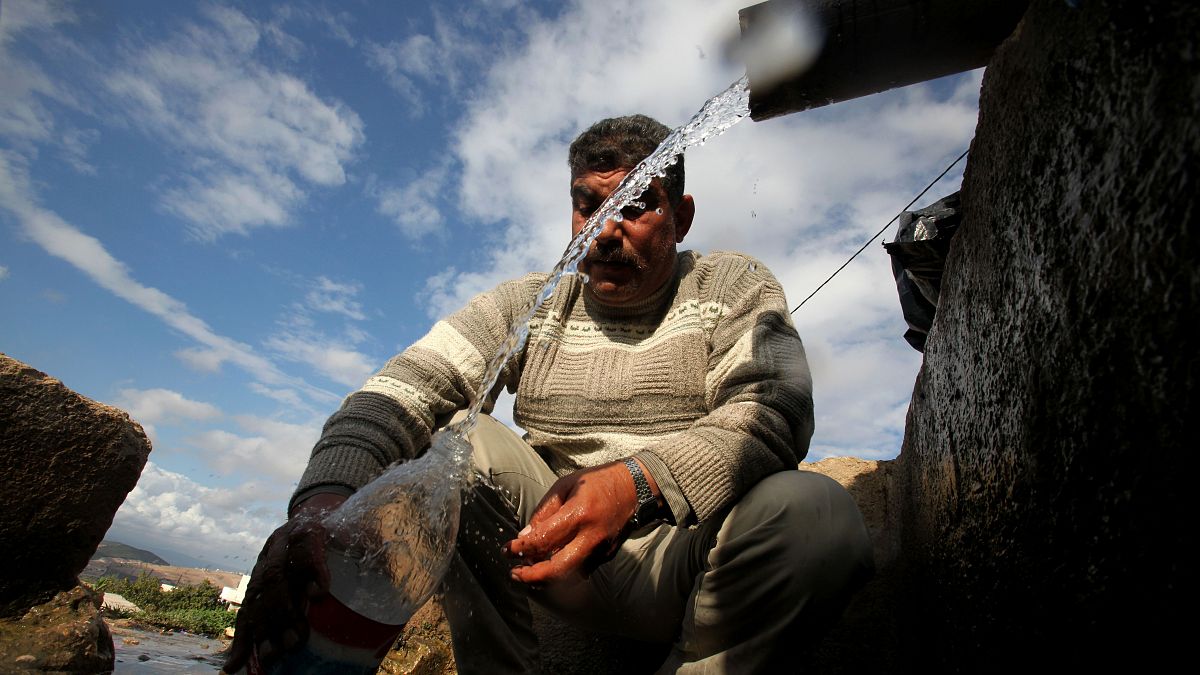 صورة من الارشيف - فلسطيني يملأ زجاجة بالمياه، عند نافورة  بالقرب من مخيم البقعة للاجئين الفلسطينيين في عمان
