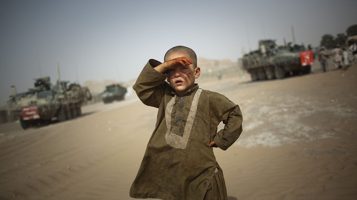طفل ينظر إلى عربات عسكرية في ضواحي سبين بولداك جنوب شرقي قندهار في أفغانستان. 2009/08/06