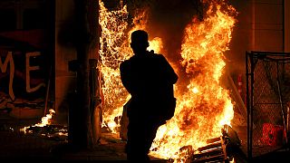 Protesters light a portable bathroom on fire during demonstrations in downtown Portland, Oregon on Friday night