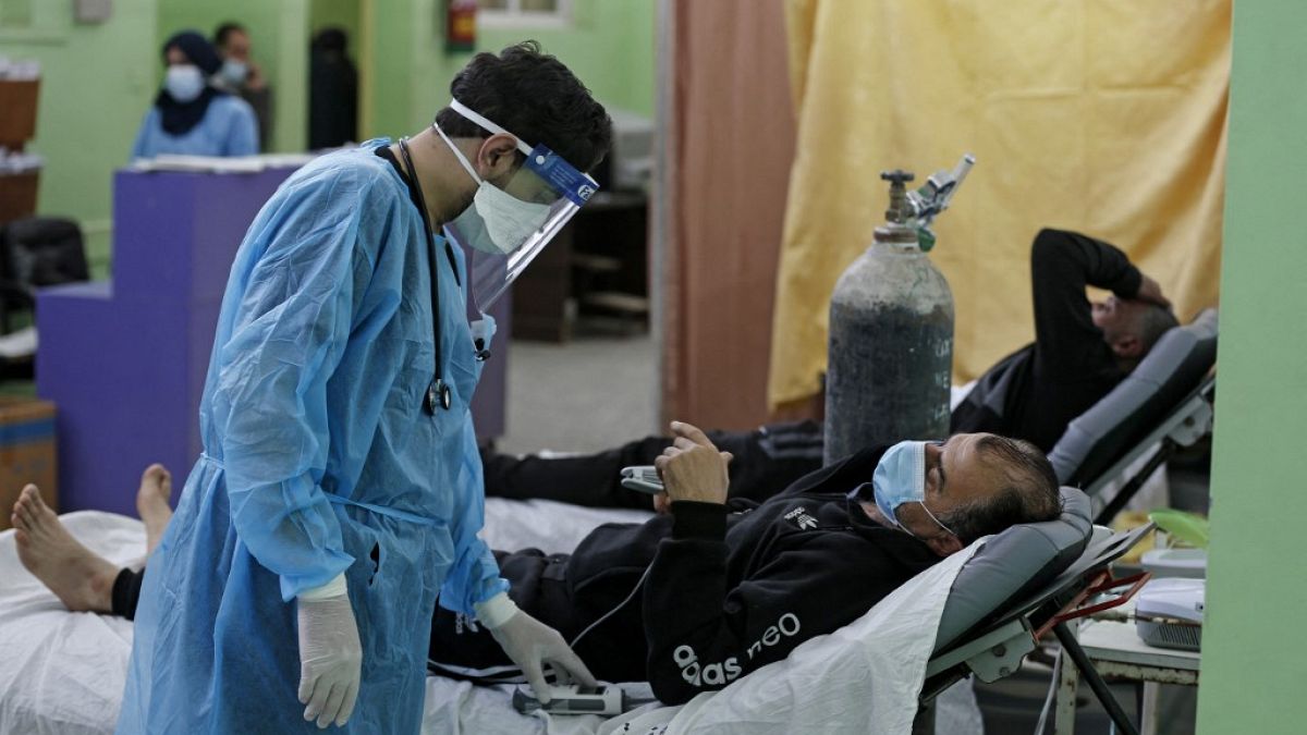 مسعف فلسطيني يعتني بمريض كوفيد -19 في وحدة العناية المركزة في مستشفى الشفاء في غزة، أبريل، 2021