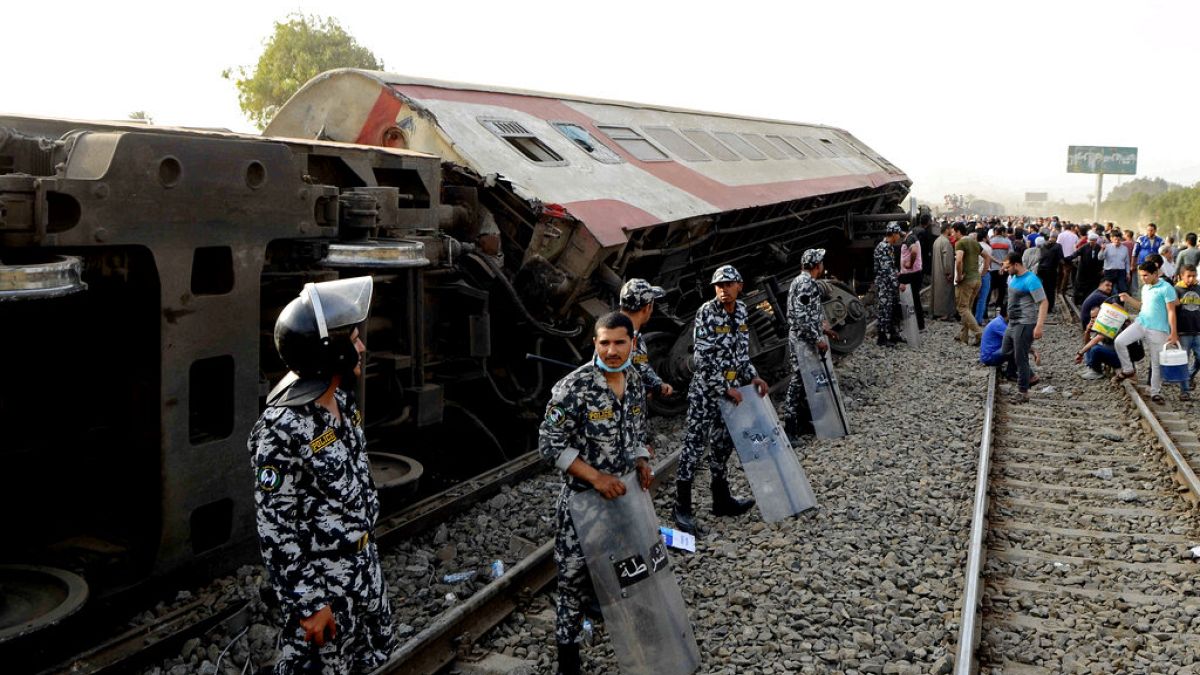 Security forces stand guard as people gather at the site where a passenger train derailed, killing 11 and injuring at least 100 people, near Banha in Egypt