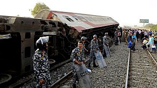 Security forces stand guard as people gather at the site where a passenger train derailed, killing 11 and injuring at least 100 people, near Banha in Egypt