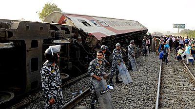 Security forces stand guard as people gather at the site where a passenger train derailed, killing 11 and injuring at least 100 people, near Banha in Egypt