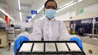 Az Intel maláj gyárának munkatársa mutatja a cég új fejlesztésű processzorait
