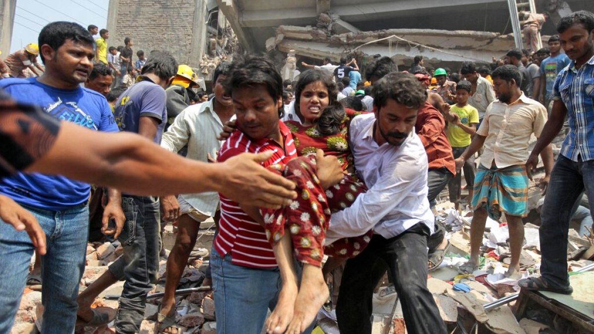 Rescuers assist an injured woman after an eight-story building housing several garment factories collapsed in Savar, near Dhaka, Bangladesh, Wednesday, April 24, 2013