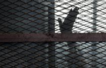 أحد المعقلين يلوح بيده من قفص الإتهام في قاعة محكمة بسجن طرة، جنوب القاهرة، مصر 22 آب/أغسطس 2015