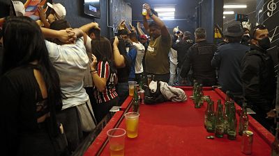 People wait to be frisked inside a bar during a civil police operation against illegal parties in Sao Paulo.