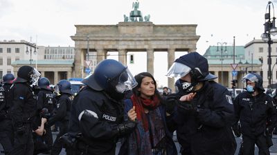 Police officers carry away a demonstrator after police stop a protest rally against the German government's policy to battle the corona virus pandemic.