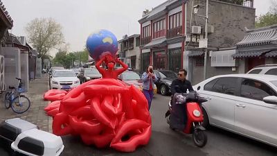 Kong posing in dress made up of giant inflatable red lips and red wires.