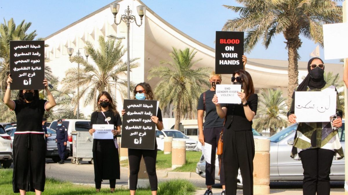  كويتيات يرفعن لافتات خلال تجمع للتنديد بالعنف ضد المرأة، خارج مجلس الأمة، في العاصمة الكويت، في 22 أبريل 2021، بعد مقتل فرح حمزة