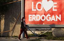 A woman wearing a face mask walks by a poster that reads "Love Erdogan" in the Turkish occupied area at the Turkish Cypriot breakaway north part of divided capital Nicosia